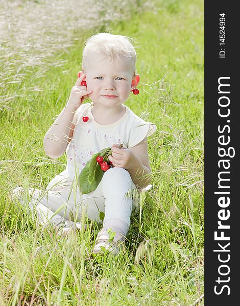 Little girl with cherries sitting on grass. Little girl with cherries sitting on grass