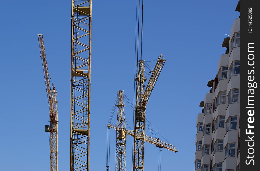 Elevating construction crane against the blue sky in a fair weather