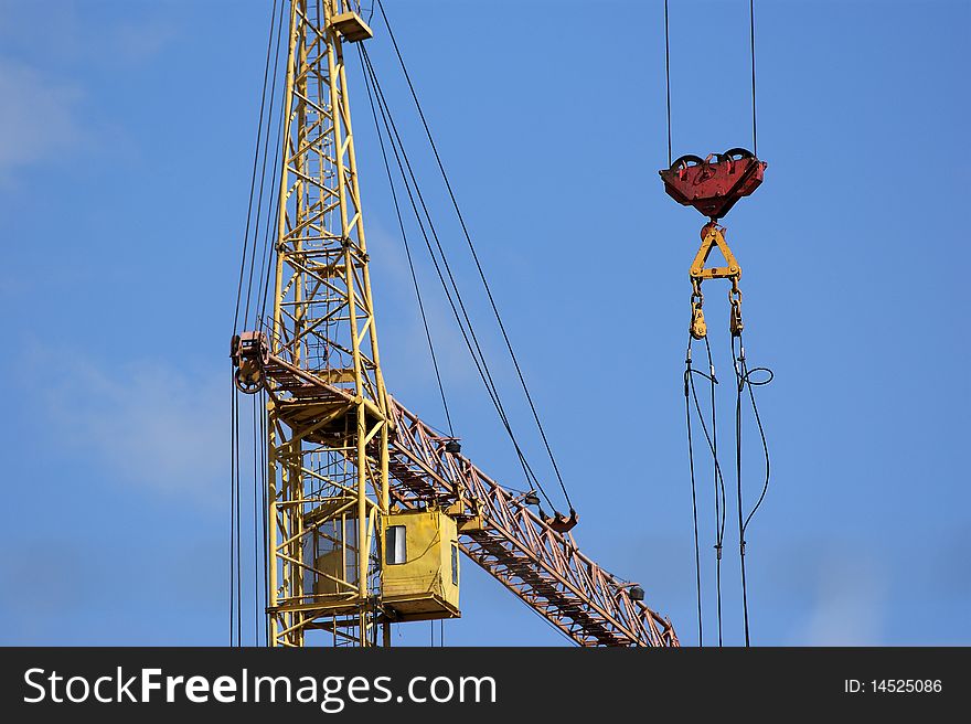 Elevating construction crane against the blue sky in a fair weather