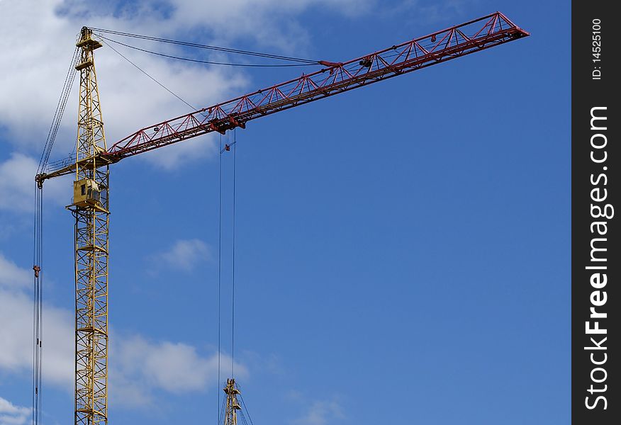 Building crane at the background of a multi-storey building under construction