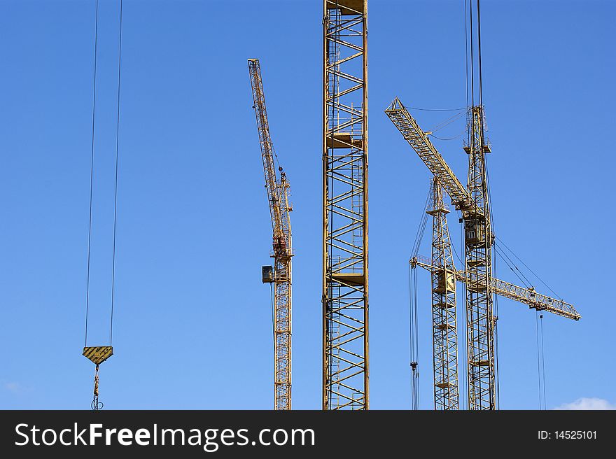 Elevating construction crane against the blue sky in a fair weather