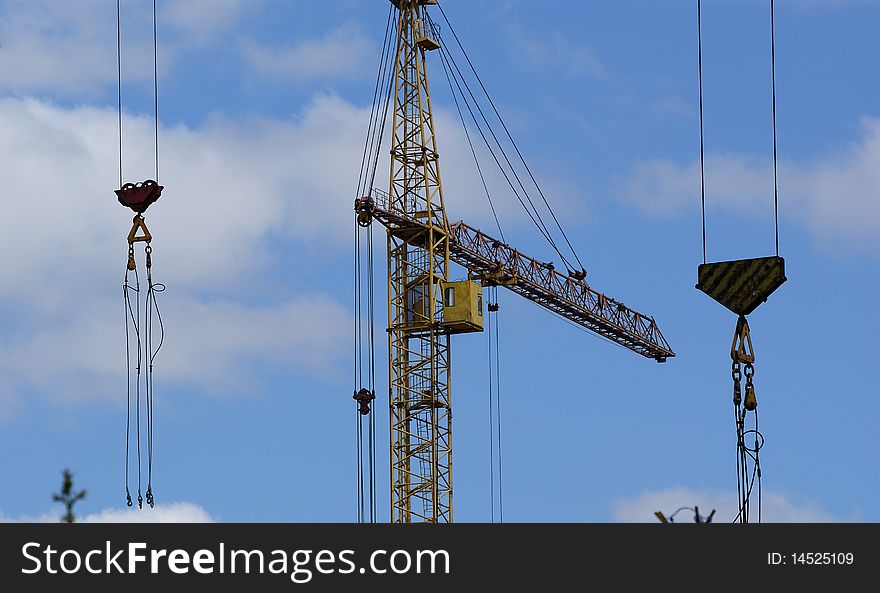 Elevating construction crane against the blue sky in a fair weather