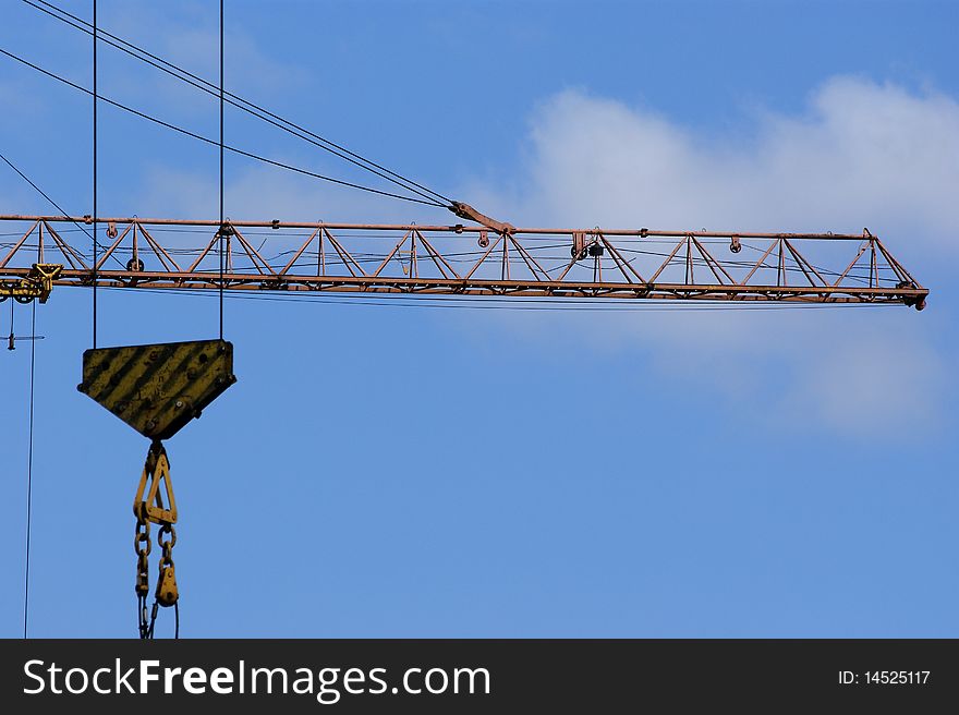 Elevating construction crane against the blue sky in a fair weather