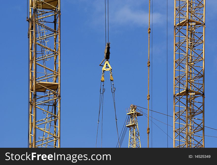 Elevating construction crane against the blue sky in a fair weather