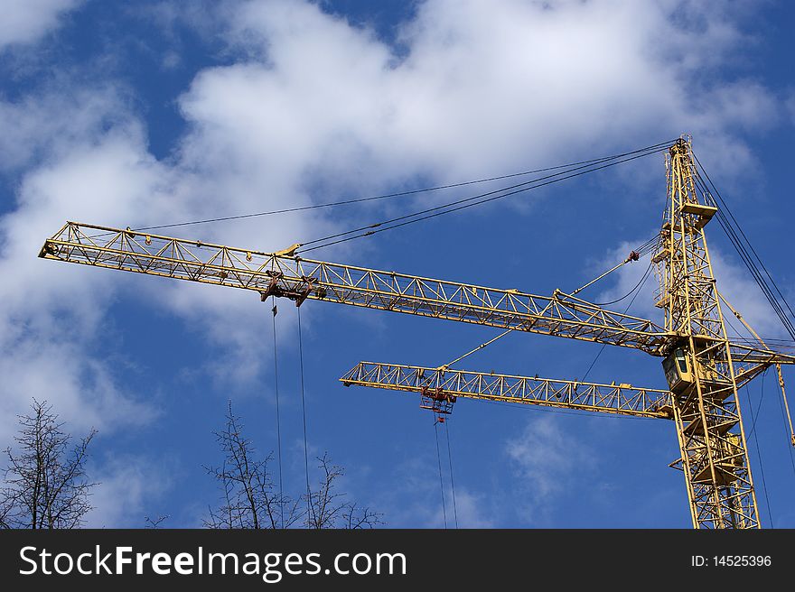 Elevating construction crane against the blue sky in a fair weather