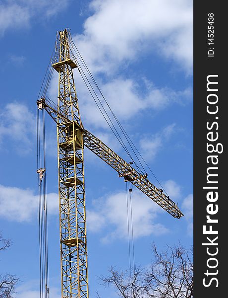 Elevating construction crane against the blue sky in a fair weather