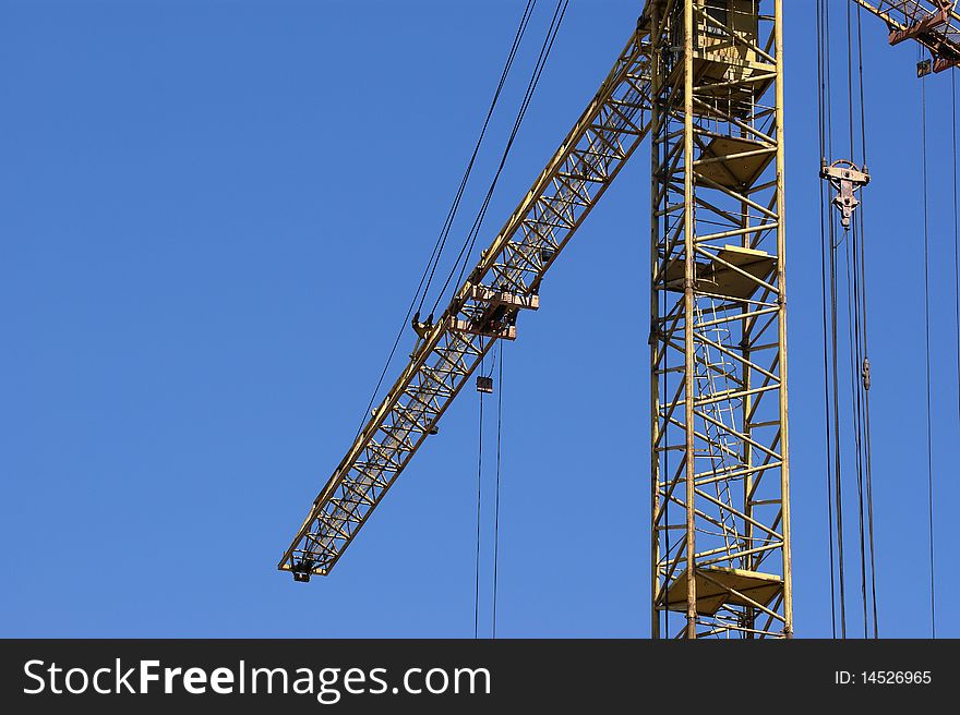 Elevating construction crane against the blue sky in a fair weather