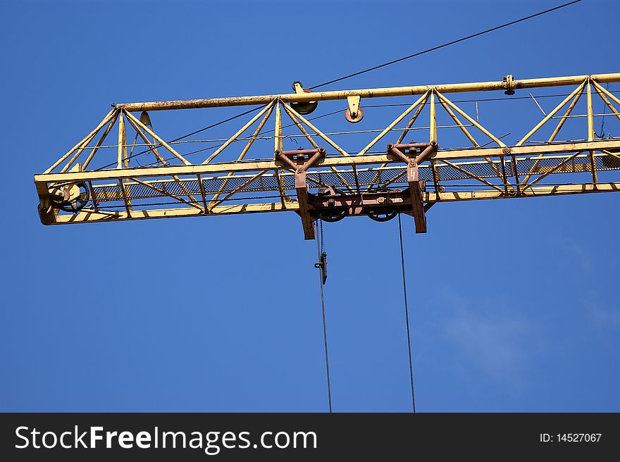 Elevating construction crane against the blue sky in a fair weather