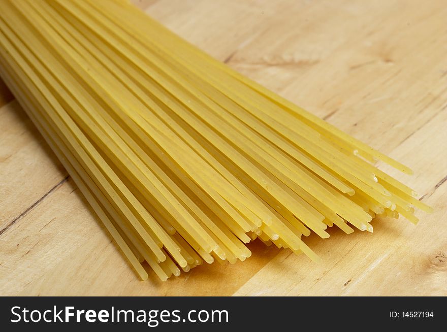 Wisp of raw spaghetti over wooden desk macro shot