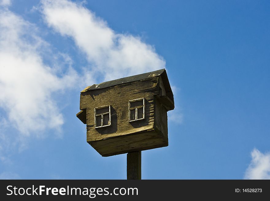 Old wooden birdhouse over blue sky