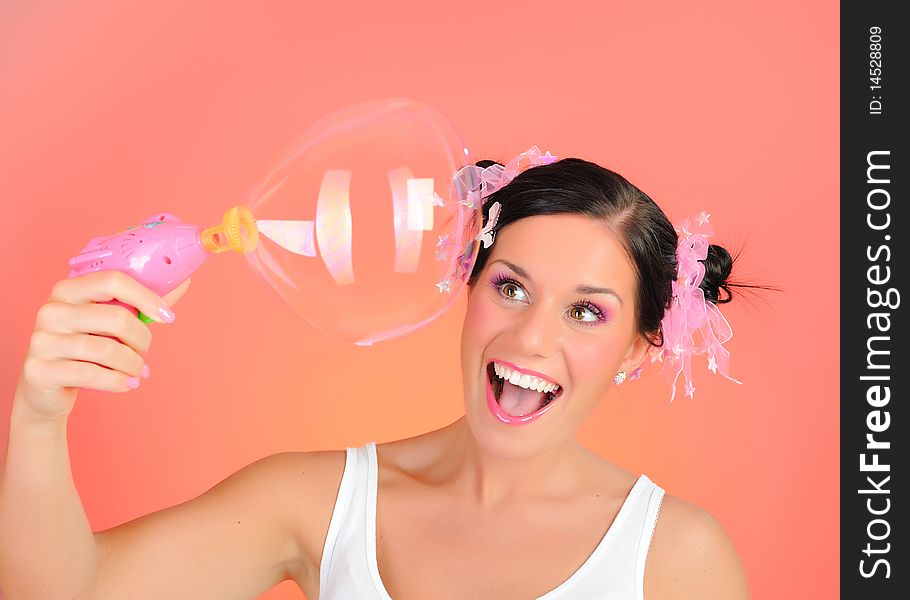 Beautiful happy teenage girl blowing soap bubbles and havinh fun. pink background