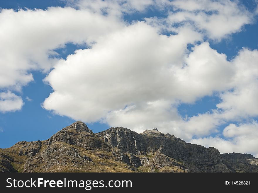 Mountain peak with fluffy white clouds and bule skies above. Mountain peak with fluffy white clouds and bule skies above