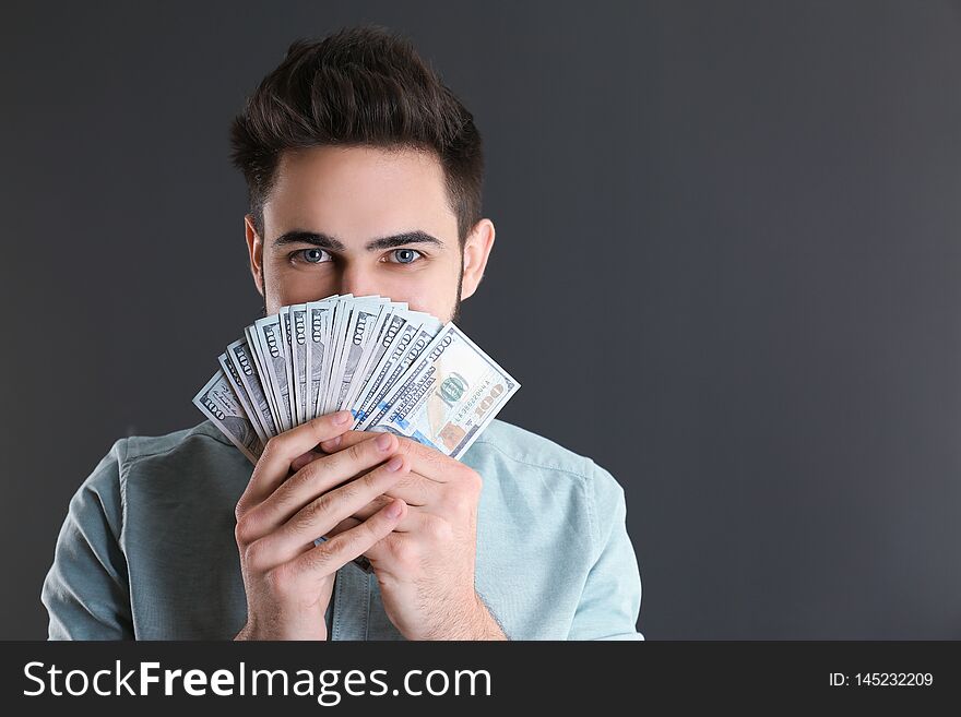 Happy young man with money on grey background