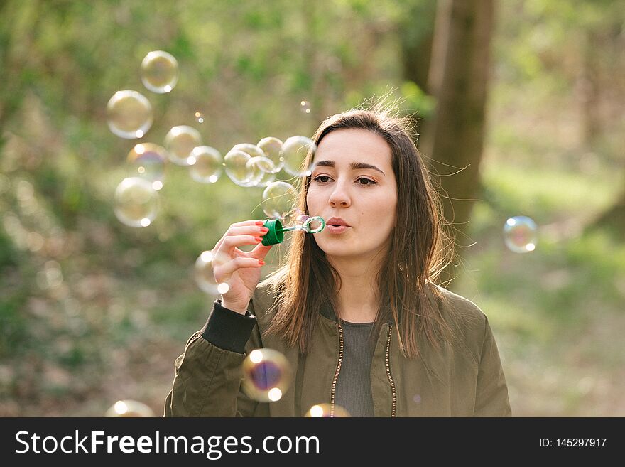 Young woman blowing soap bubbles in the woods. Freedom, lifestyle and networking concept. Colorful vintage analog film look.