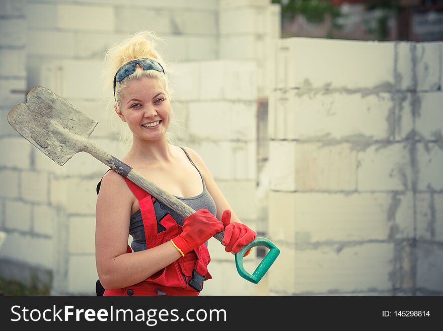 Woman worker using shovel standing on industrial construction site, working hard on house renovation. Woman worker using shovel standing on industrial construction site, working hard on house renovation