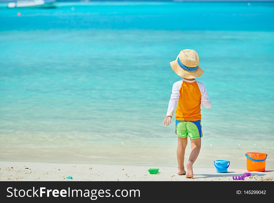 Three year old toddler boy playing with beach toys on beach. Summer family vacation at Maldives. Three year old toddler boy playing with beach toys on beach. Summer family vacation at Maldives