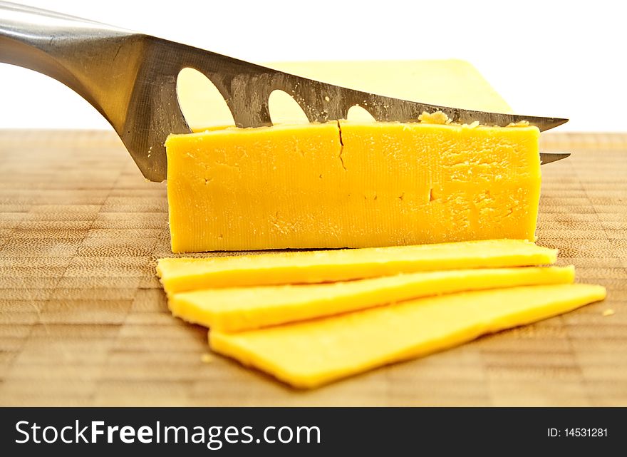 Slicing Gouda with a cheese knife on a wooden board. Slicing Gouda with a cheese knife on a wooden board