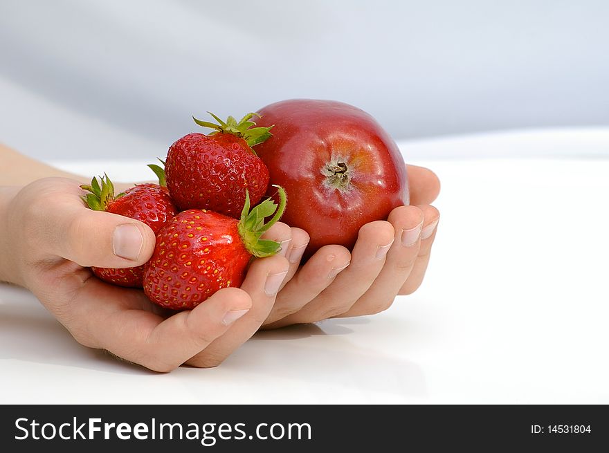 Child holds in the hands apple and strawberries. Child holds in the hands apple and strawberries