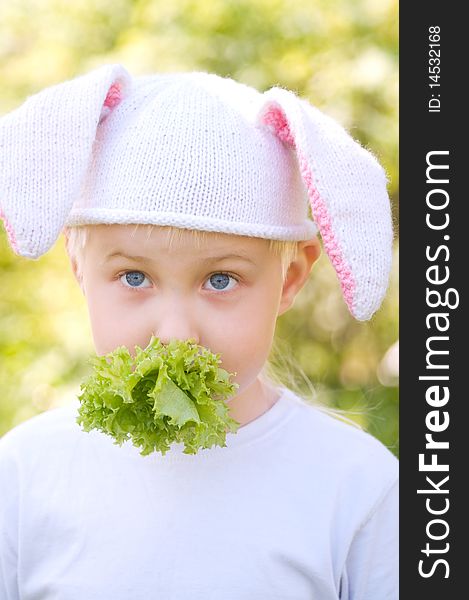 Portrait of the little boy in a cap with bunny ears and eating lettuce. Portrait of the little boy in a cap with bunny ears and eating lettuce