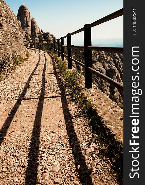 A dusty track in rocky mountains in montserrat, spain, showing hand railings and clear blue sky. A dusty track in rocky mountains in montserrat, spain, showing hand railings and clear blue sky