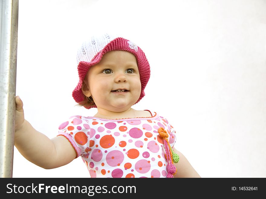 The joyful little girl in a dress and a hat looks forward. The joyful little girl in a dress and a hat looks forward