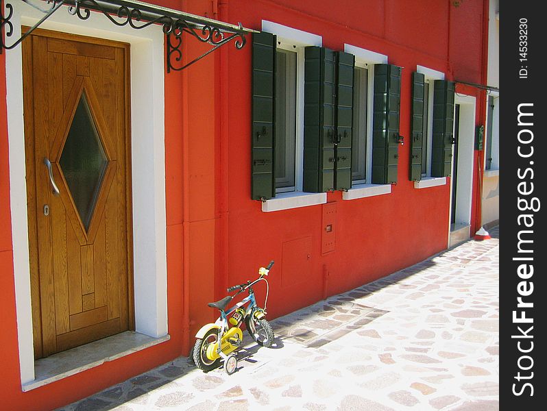 The red house wall and yellow сhildren's bicycle