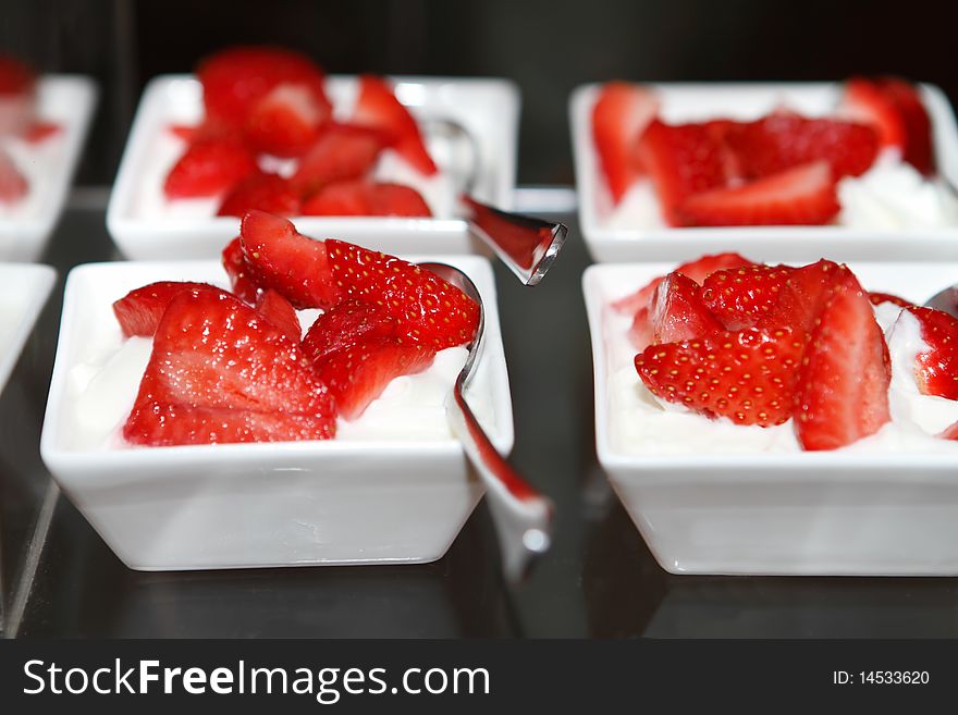 Fresh strawberries with whipped cream in dishes on the table