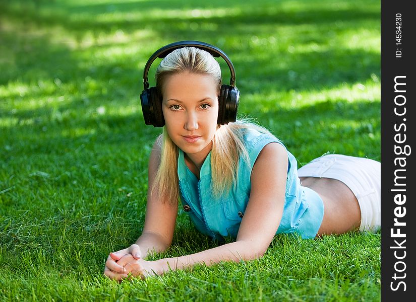 Girl listening music on headphones, on grass