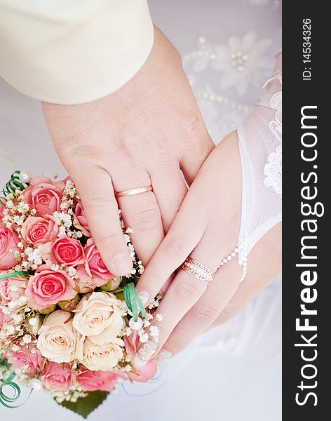 Wedding rings on hands with a bouquet