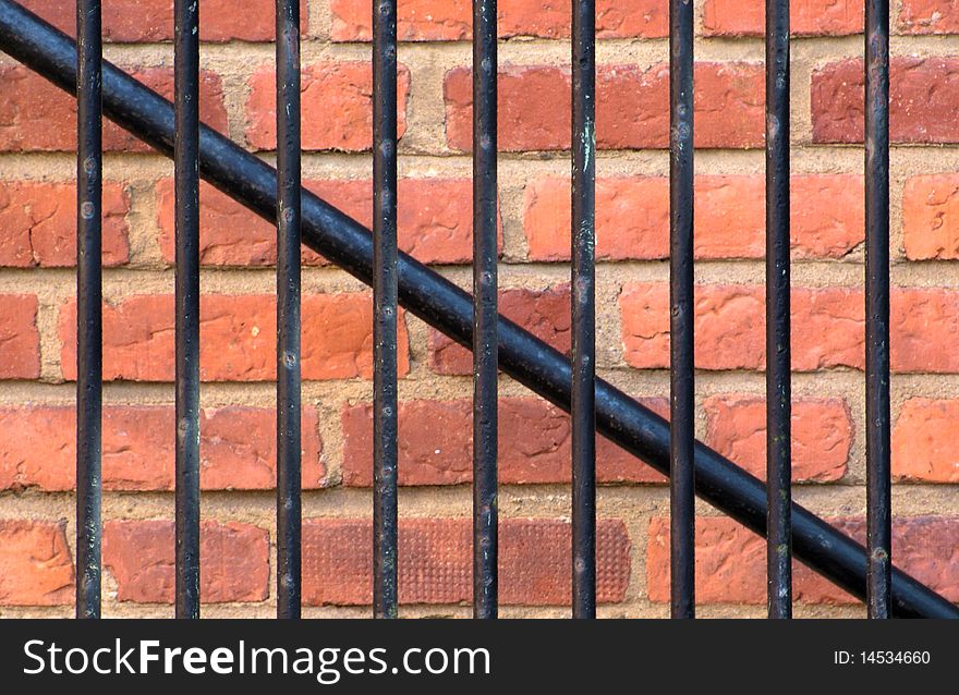 Fence with banister against brick wall.