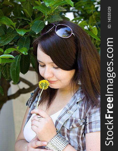 Young dark-haired girl sniffs a dandelion. Young dark-haired girl sniffs a dandelion