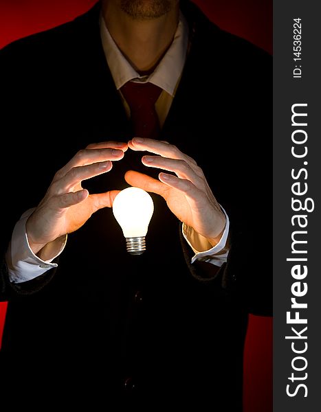 Businessman holding a light bulb on red background. Businessman holding a light bulb on red background