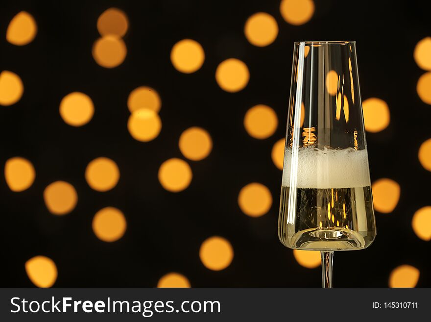 Glass of champagne against blurred lights. Space for text