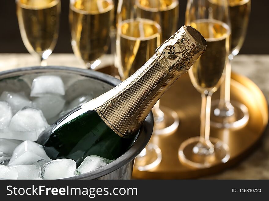 Bottle of champagne in bucket with ice cubes on table