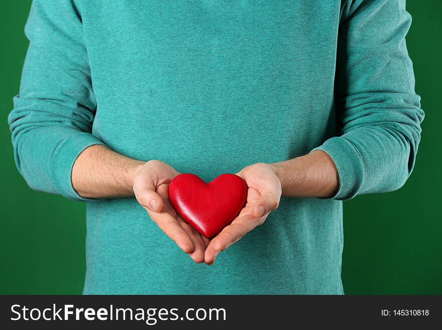 Man holding decorative heart on color background
