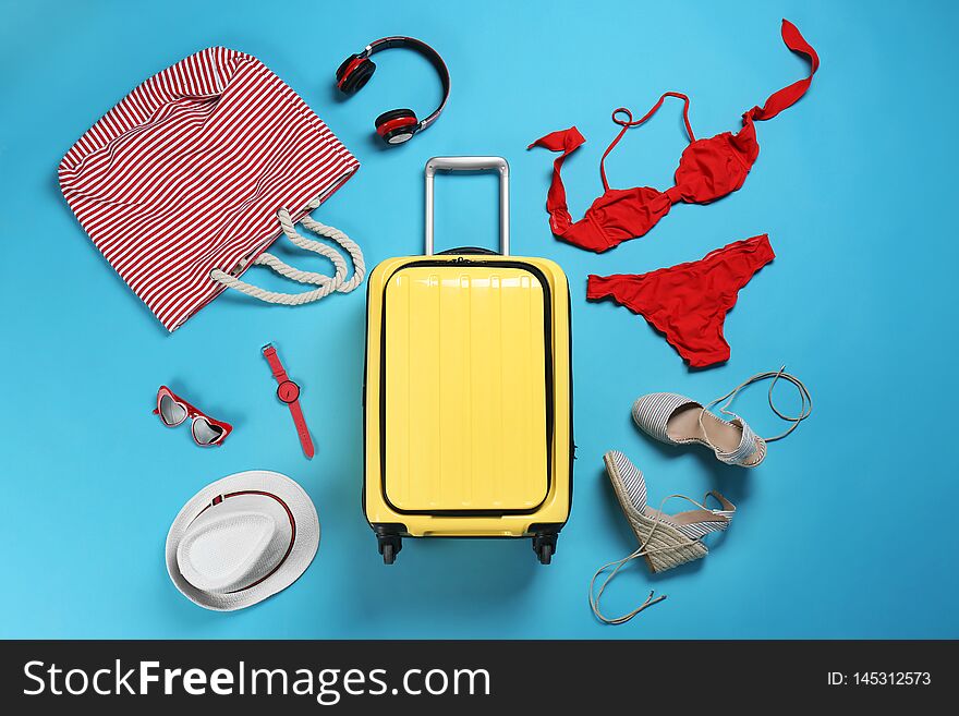 Flat lay composition with suitcase and accessories on color background.