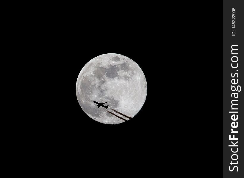 A commercial airliner at high altitude is silhouetted as it passes in front of a full moon at night 2 of 3. A commercial airliner at high altitude is silhouetted as it passes in front of a full moon at night 2 of 3