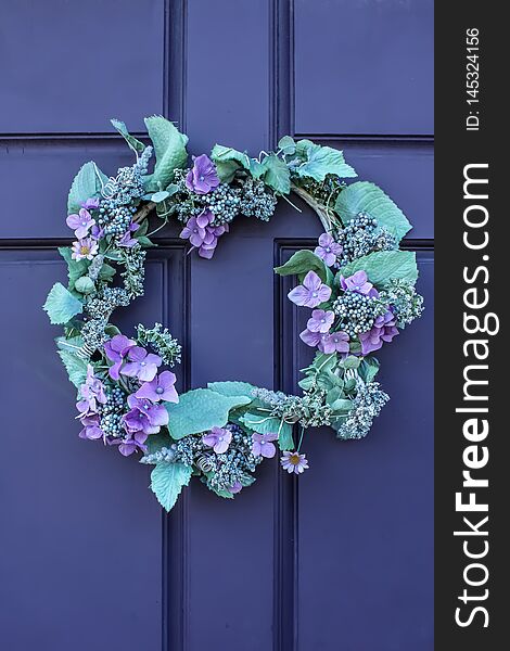 Close-up of beautiful green and purple wreath on deep purple wooden door
