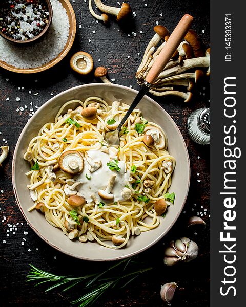 Pasta with mushrooms, sauce, herbs and spices in bowl. On dark rustic background