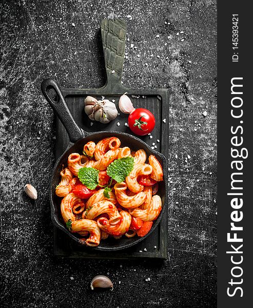 Pasta In Pan On A Cutting Board With Garlic,tomato And Mint Leaves