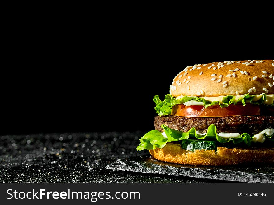 Burger with juicy beef,tomatoes and salad. On rustic background