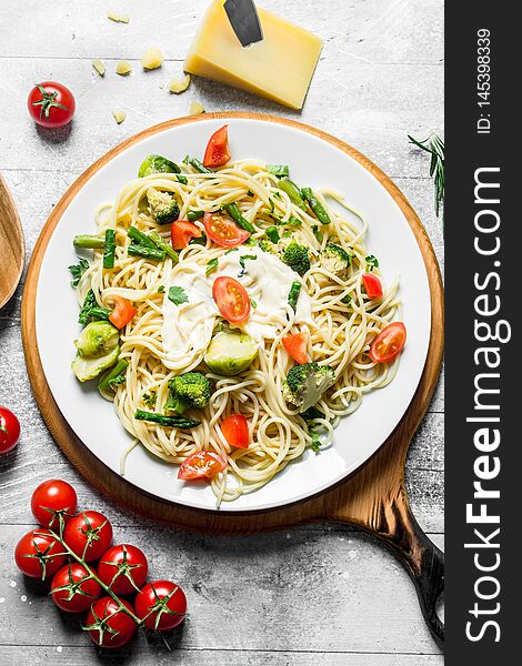 Pasta with vegetables and tomatoes on a branch. On white wooden background