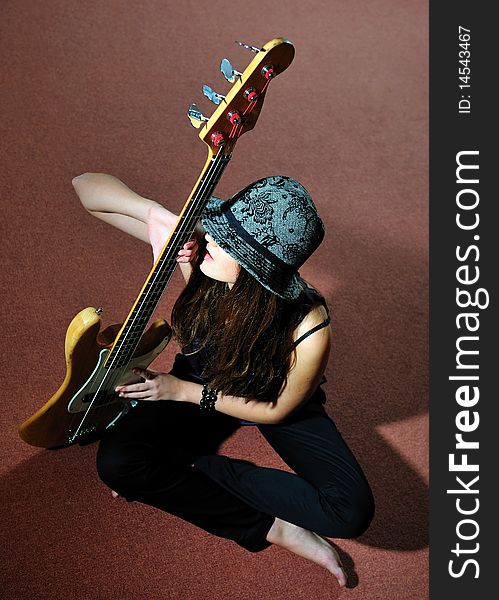 Young pretty woman with guitare sitting on the floor