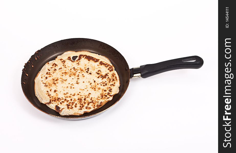 Pancake cooking in a pan on white