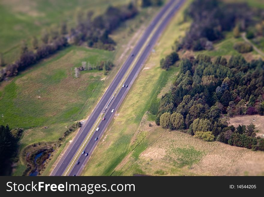 Highway panorama with cars in motion along fields and woods, New Zealand