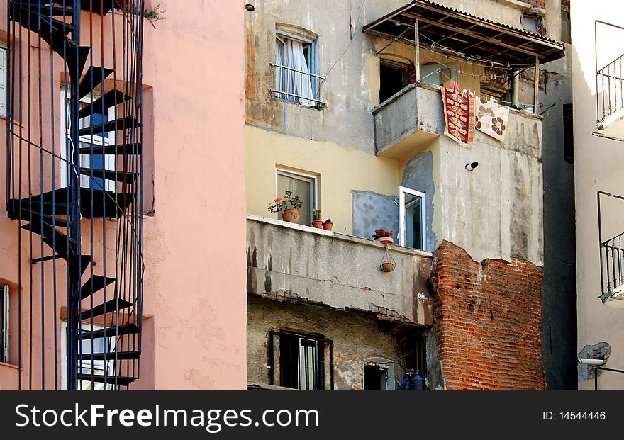 Underprivileged Areas Of City. Closeup of old building with spiral staircase flowerpots and small balcony