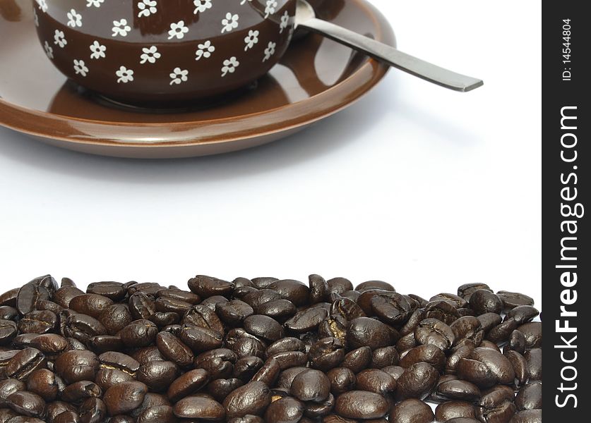 Coffee beans in foreground with cup and saucer. Coffee beans in foreground with cup and saucer