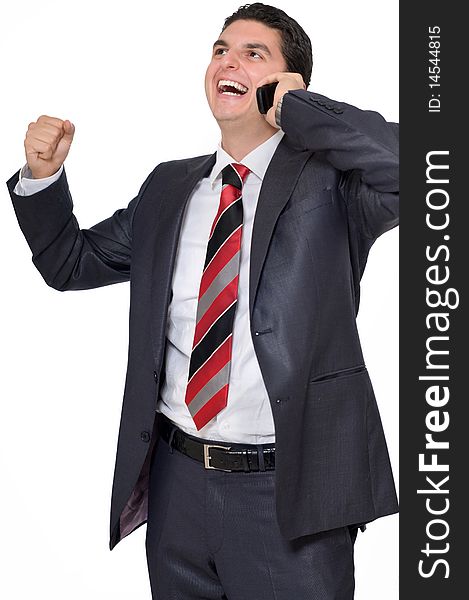 A young businessman on the phone smiling and holding a fist with excitement. A young businessman on the phone smiling and holding a fist with excitement.