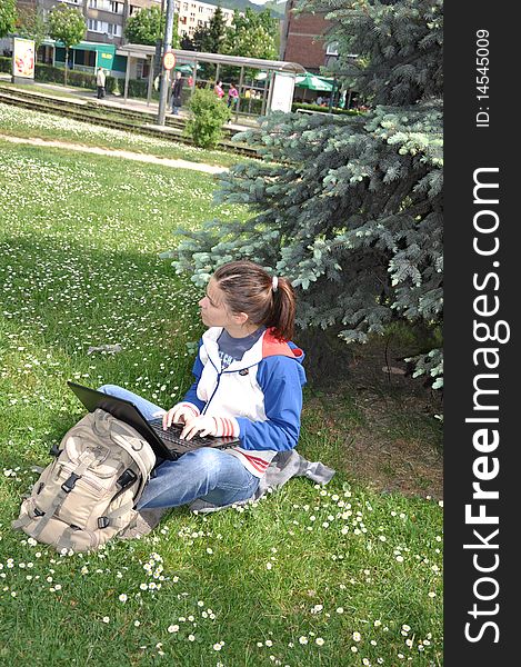 Young student learning outdoors with laptop