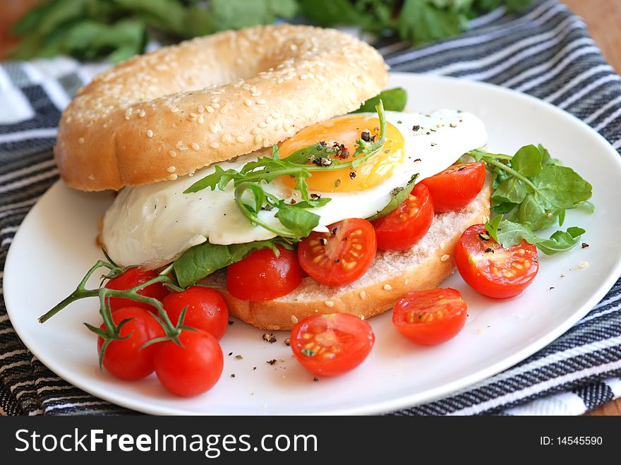 Bagel filled with cherry tomatoes, rocket and fried egg. Bagel filled with cherry tomatoes, rocket and fried egg